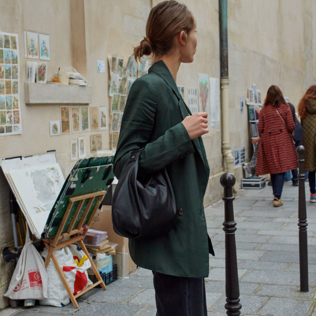 woman standing on sidewalk in Paris carrying Aoyama crossbody leather bag as a handbag