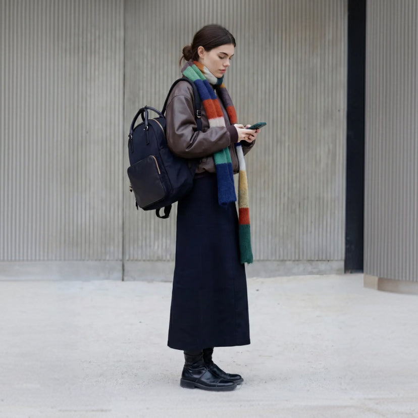 Woman carrying in her hands a Lo & Sons Rowledge 2 backpack walking down the sidewalk in gym outfit