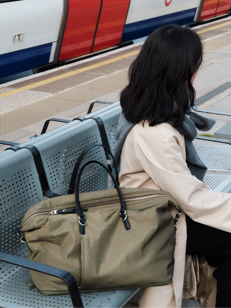 Woman standing in hotel lobby with Lo & Sons Catalina Deluxe weekender bag