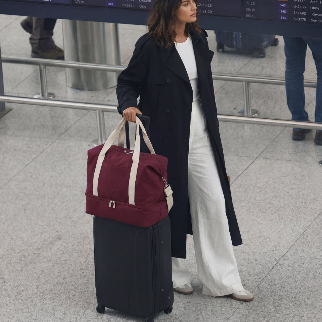 woman with Catalina Deluxe in Cabernet canvas and suitcase traveling at the airport
