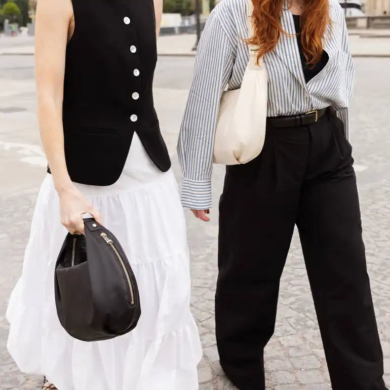 two women walking down the street in Paris carrying the Lo & Sons Aoyama leather crescent handbag and purse in black and ivory colors