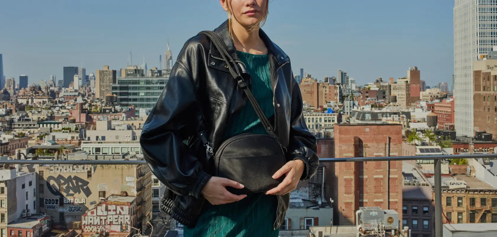 Woman holding the Lo & Sons Nouvelle crossbody bag in black on a rooftop in New York City