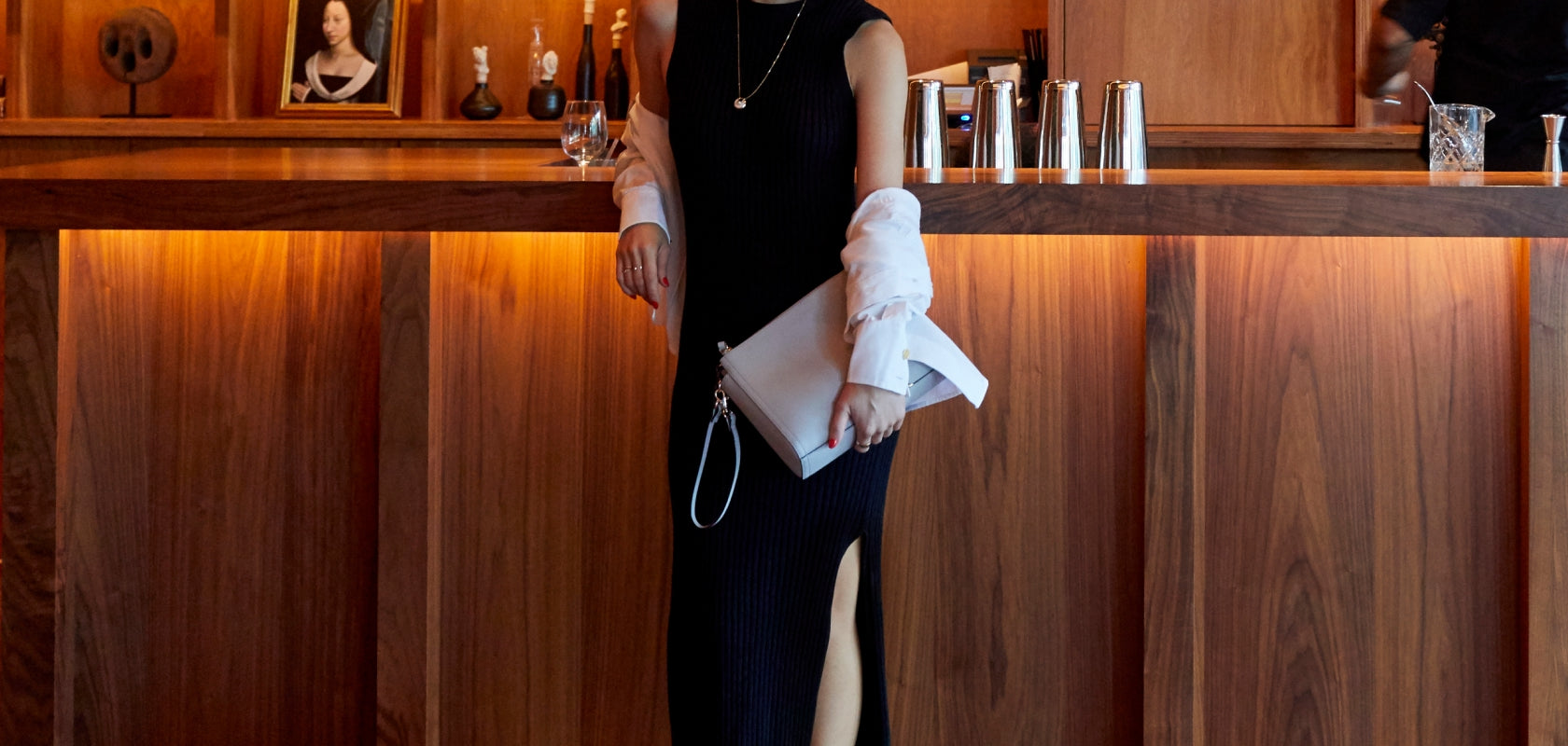 woman in a chic bar carrying the Lo & Sons Pearl leather bag as a large wristlet