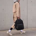 Woman in casual outfit walking around a city carrying a Lo & Sons Rowledge backpack and tote