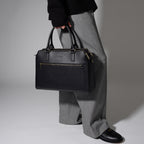 Trinity leather laptop tote in black held in hands in a studio