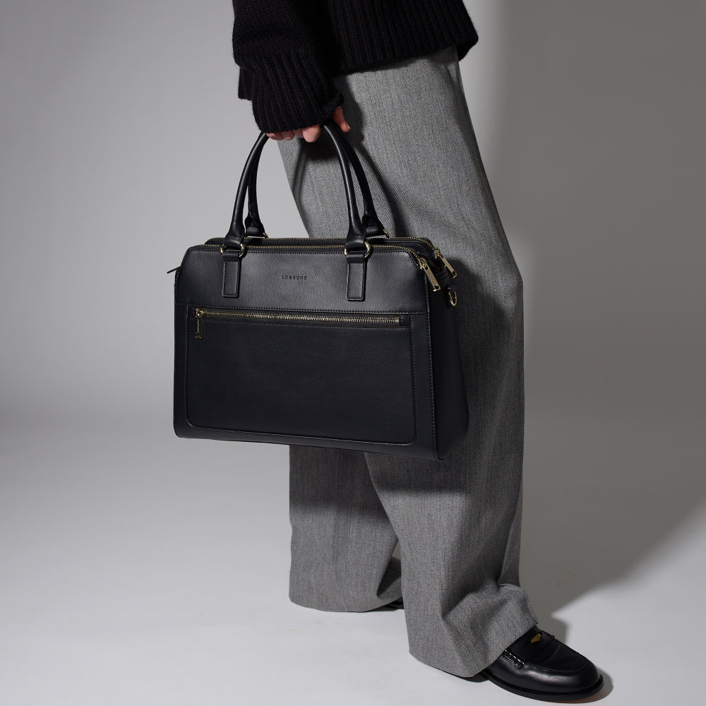 Trinity leather laptop tote in black held in hands in a studio