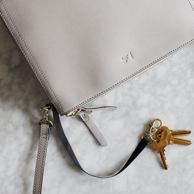 key leash feature of the Lo & Sons Pearl crossbody bag in light grey saffiano