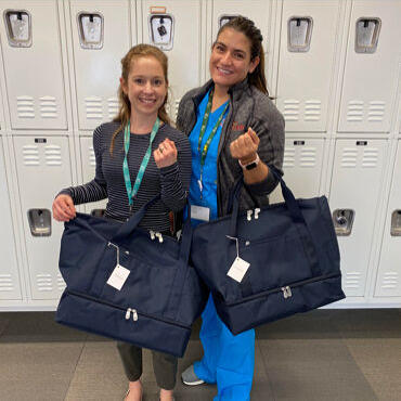 Female medical professionals with Lo & Sons Catalina Deluxe bags at a hospital during the COVID-19 pandemic