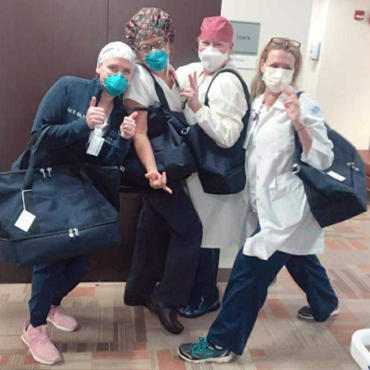 Female medical professionals with Lo & Sons Catalina Deluxe bags at a hospital during the COVID-19 pandemic