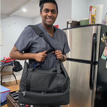 Male medical professional with Lo & Sons Catalina Deluxe bag at a hospital during the COVID-19 pandemic