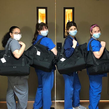 Female medical professionals with Lo & Sons Catalina Deluxe bags at a hospital during the COVID-19 pandemic