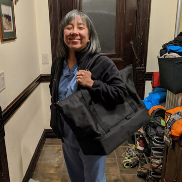 Female medical professional with Lo & Sons Catalina Deluxe bag at a hospital during the COVID-19 pandemic