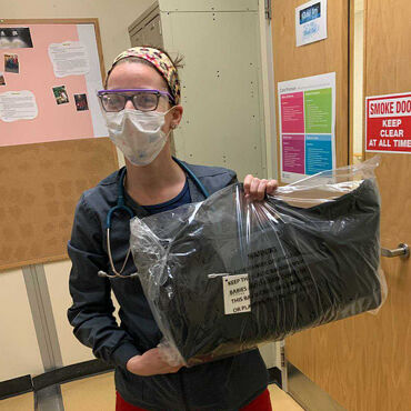 Female medical professional with Lo & Sons Catalina Deluxe bag at a hospital during the COVID-19 pandemic