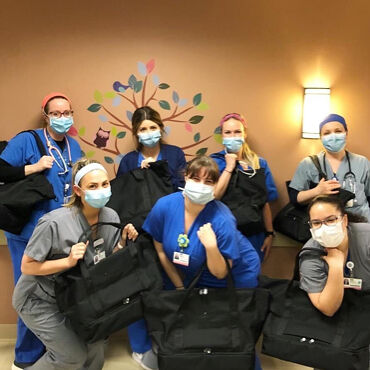 Female medical professionals with Lo & Sons Catalina Deluxe bags at a hospital during the COVID-19 pandemic