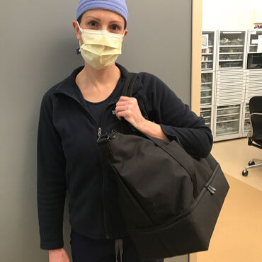 Female medical professional with Lo & Sons Catalina Deluxe bag at a hospital during the COVID-19 pandemic