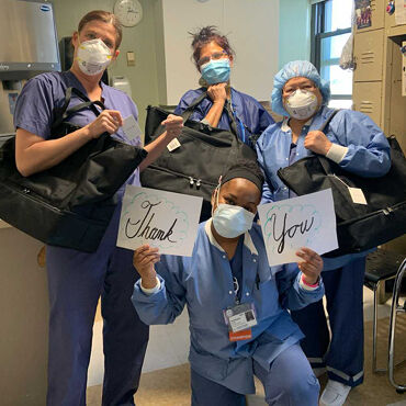 Female medical professionals with Lo & Sons Catalina Deluxe bags at a hospital during the COVID-19 pandemic